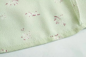 Detail eines hellgrünen Blumenkleides aus Chiffon mit präzisen Nähten und Saumqualität