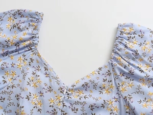 Détail de l'encolure carrée et zip arrière d'une robe ajustée à fleurs et manches bouffantes