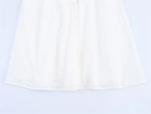 Detail of white lace embroidery dress with delicate eyelet pattern and covered buttons