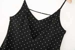 Detail of elegant black and white polka dot sleeveless dress with slim straps and deep V-neck