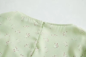 Nahaufnahme eines hellgrünen Blumenkleides mit Rundhalsausschnitt und verdecktem Reißverschluss