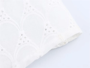 Close-up of white lace embroidery with delicate hollow-out scallop patterns on fabric