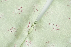 Detailaufnahme des hochwertigen unsichtbaren grünen Reißverschlusses am floralen Kleid