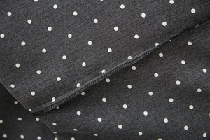 Macro detail of black polka dot fabric showing fine stitching and textile texture