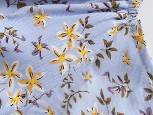 Détail du tissu à fleurs bleu montrant la texture sergé et les finitions froncées