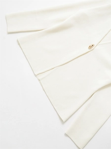 Detailed macro view of the cream knit cardigan's texture and unique gold pebble button
