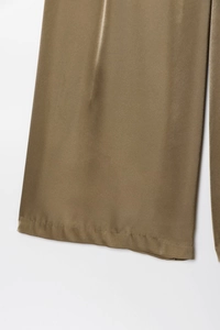 Detail view of smooth dark olive satin wide-leg trousers with premium silk texture