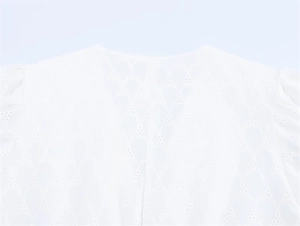 Close-up of white lace dress with intricate eyelet scale embroidery and cotton texture