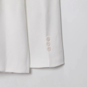 Détail de la manche d'un blazer blanc en lin avec trois boutons verticaux sur le poignet