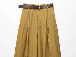 Detail of high waisted wide leg trousers with metallic satin sheen and brown leather belt