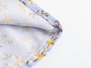 Gros plan de l'ourlet roulé sur une robe en rayonne et coton à fleurs bleu clair