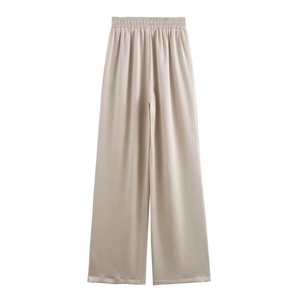 Detail view of champagne pleated wide-leg trousers with elastic waist and soft draping fabric