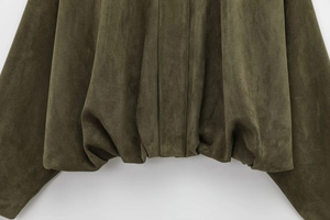 Detail of dark green suede fabric showing high-quality stitching and loose hemline