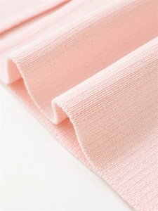 Close-up of soft pink knit fabric texture showing fine weave and premium material detail