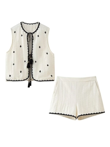 Detailed close-up of beige cotton linen set featuring black embroidery and tassel ties