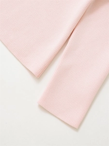 Close-up of pink knit cardigan detailing the fine stitching on cuffs and hemline