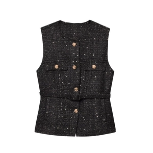 Close-up of black tweed vest featuring sequined fabric and gold embossed buttons