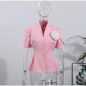 Détail de chemisier rose à manches courtes avec col en V et grande rose blanche décorative