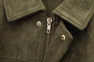 Detailed close-up of metallic zipper and snap button on olive green suede jacket collar