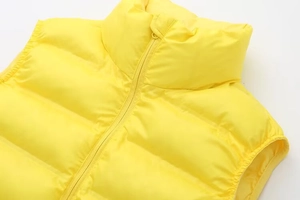 Detail of bright yellow down vest showing waterproof fabric and stand collar zipper