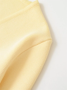 Detailed close-up of light yellow knit fabric showing fine texture and shoulder stitching