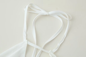 Détail du col licou blanc noué en ruban sur un tissu doux et élégant de qualité