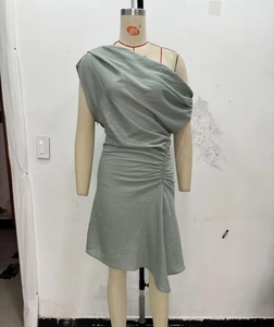 Détail de la robe asymétrique vert sauge avec fronces latérales et coupe irrégulière à l'épaule