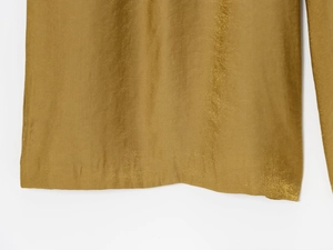 Macro shot of shimmering metallic gold fabric texture and fine stitched hem details