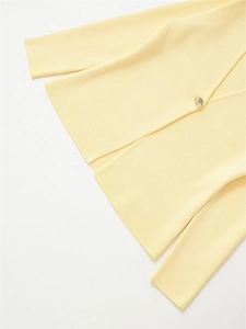 Detailed macro view of soft yellow ribbed knit fabric with a shiny gold metallic button