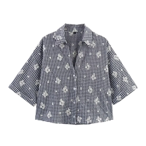 Detail of embroidered floral patterns on black and white gingham checkered shirt