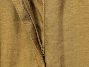 Detailed close-up of high-quality YKK zipper on golden brown satin wide-leg pants