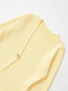 Close-up of ribbed knit sweater texture with V-neck and decorative gold irregular button