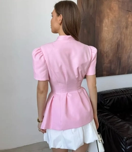 Détail d'un blazer rose à manches courtes avec épaules bouffantes et taille cintrée