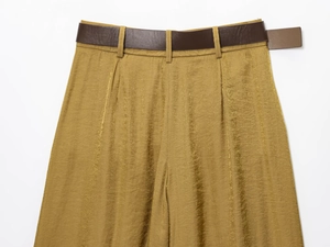 Detail of high-waist wide-leg pants in metallic gold satin with a brown leather belt