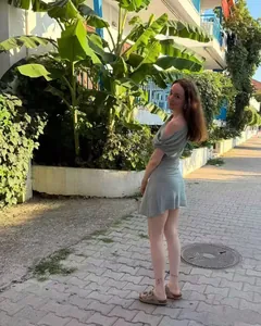 Vue de rue d'une mini robe d'été vert sauge à épaule dénudée et taille marquée