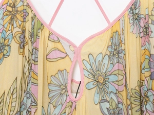 Detail of floral print summer dress with yellow fabric, thin straps and keyhole neckline