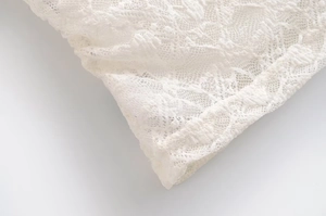 Detailed close-up of white floral lace embroidery and fine edge stitching on the top