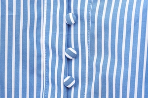 Macro view of blue and white vertical striped fabric with matching fabric-covered buttons