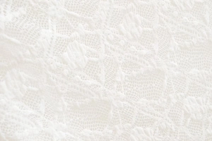 Detailed macro view of pure white lace fabric with intricate floral hollow patterns