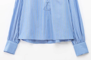 Detail of blue and white striped cotton shirt showing button cuffs and hem texture