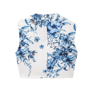 Detail of white sleeveless top featuring elegant blue lily floral patterns and light fabric