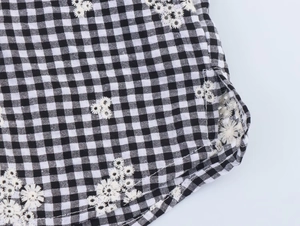 Detailed macro view of black gingham fabric featuring delicate white daisy embroidery