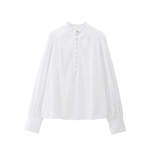 Close-up of white cotton blouse showing elegant ruffle collar and fabric covered buttons