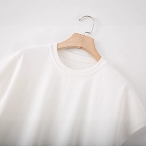 T-shirt blanc à col rond avec dentelle en relief sur cintre en bois et mur blanc pur