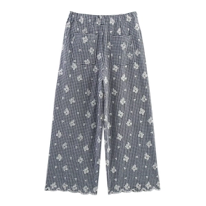 Detail of gingham trousers featuring floral embroidery and scalloped hemline edges