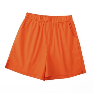 Detail view of orange sports shorts featuring elastic waistband and side split design