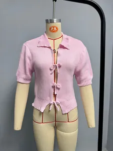 Detail of pink knitted cardigan featuring front ribbon bow ties and a polo collar