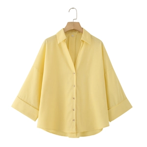Detailed view of the buttoned front and wide sleeves on a yellow linen shirt