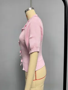 Close-up of pink knit cardigan featuring bow ribbon closures and ribbed texture details