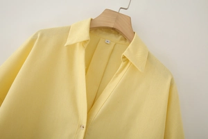 Close-up of a pale yellow linen-blend shirt collar with buttons and size S tag detail